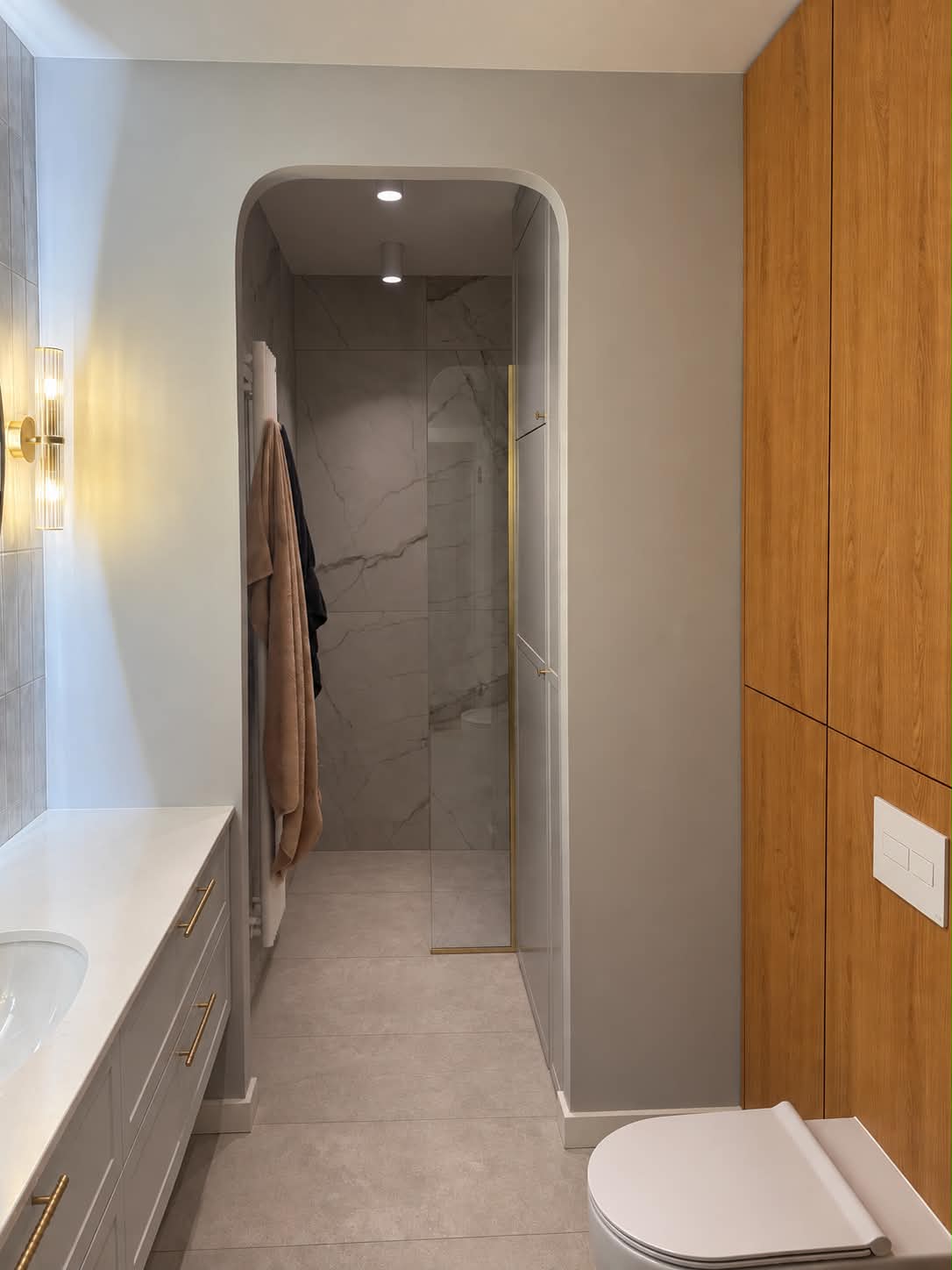The bathroom after finishing: tiled walls and floor, wooden joinery, a shower recess and a countertop basin.
