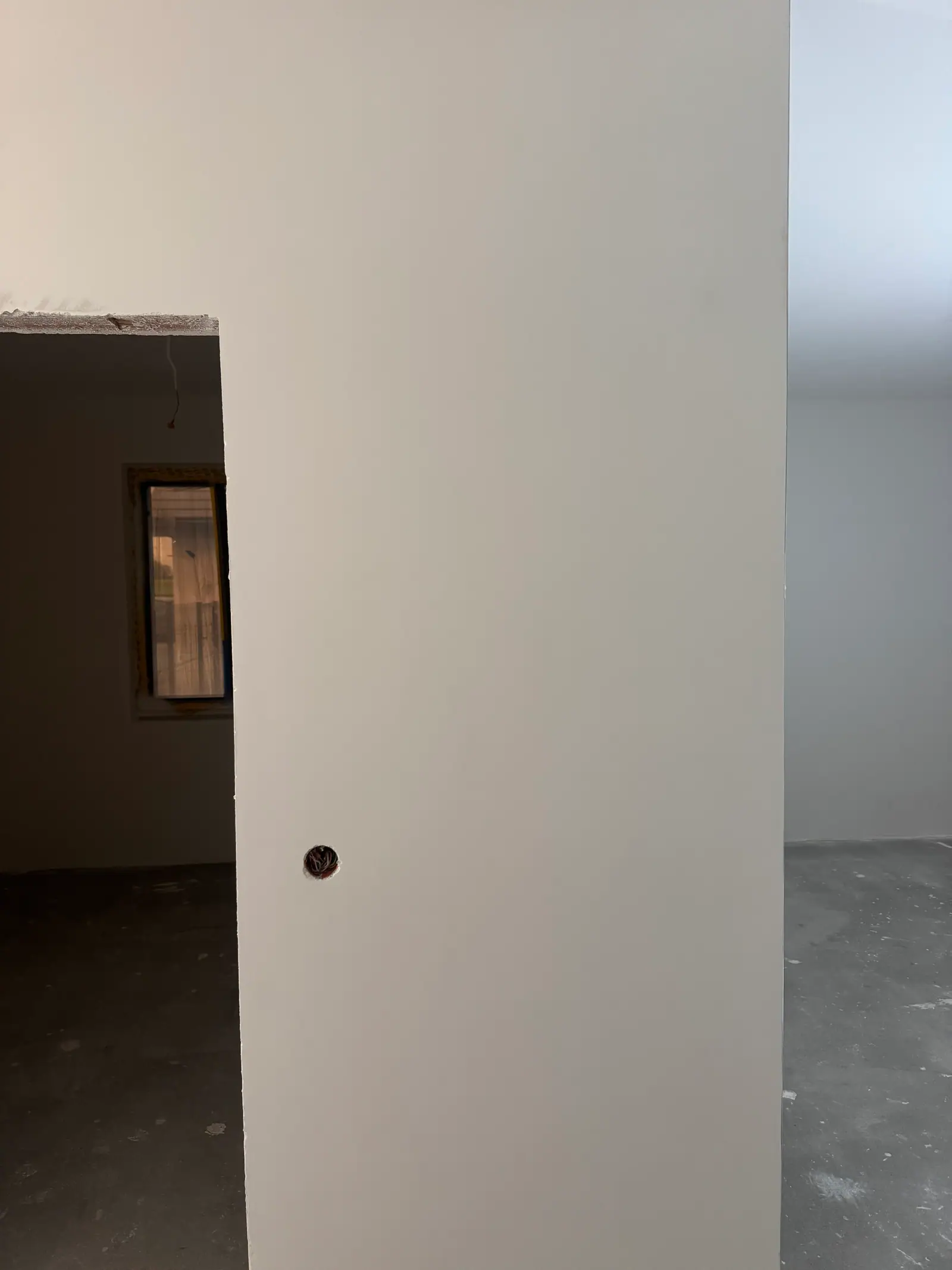 A smooth white wall beside a door opening, with another room beyond.