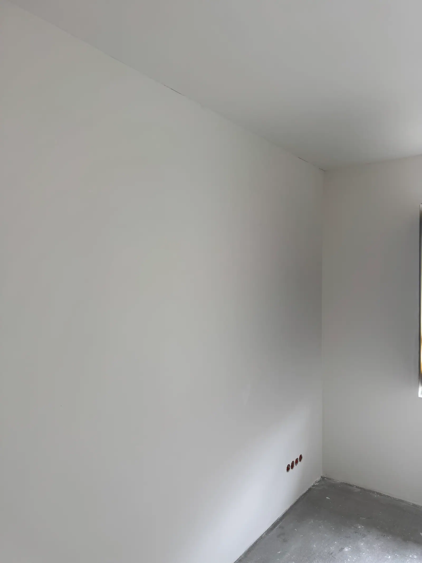 A smooth white wall and ceiling in an empty room.