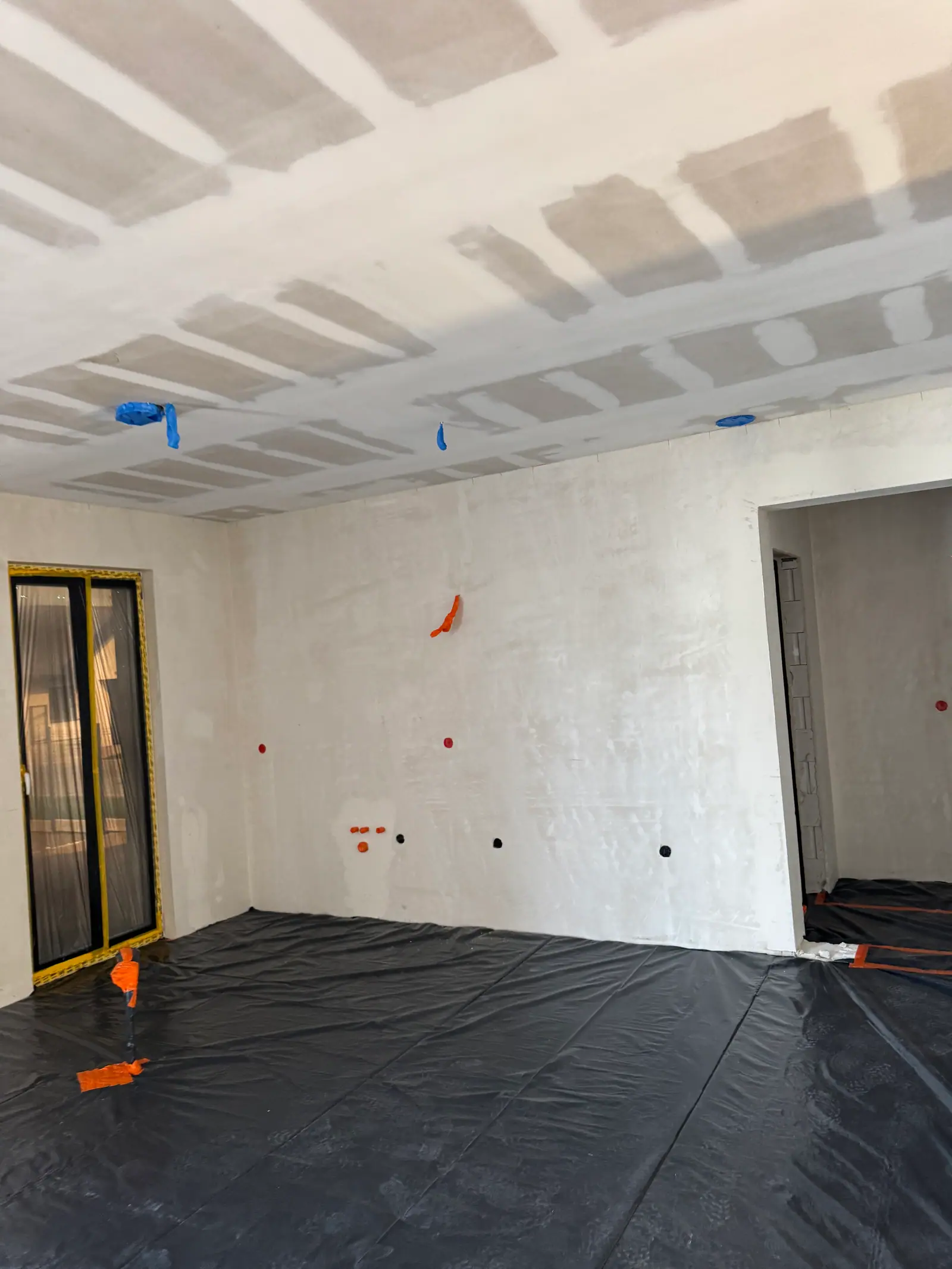 A room during the work: a ceiling with filled joints and a floor covered with black film.
